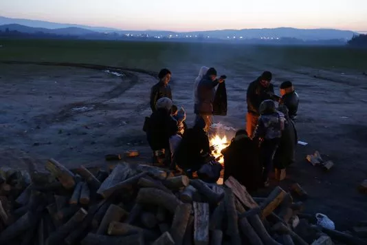 Des réfugiés se réchauffent autour d'un feu près du village frontière d'Idomeni en Grèce le 21 janvier 2016.


