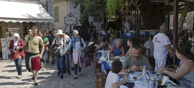 Des migrants traversent une place touristique du village grec de Skala Sikaminia, sur l'île de Lesbos. Crédits photo : Visar Kryeziu/AP/SIPA/Visar Kryeziu/AP/SIPA


