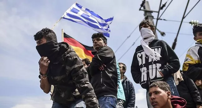 Des réfugiés et des migrants brandissent les drapeaux grec et allemand - Bulent Kilic/AFP



