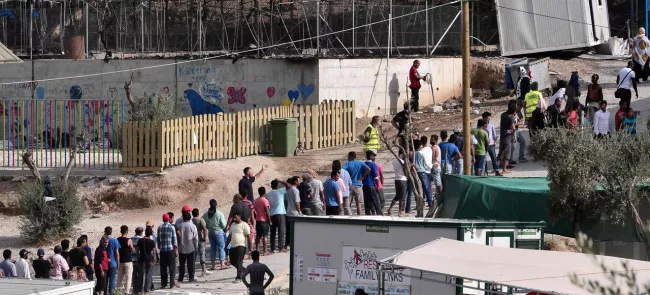 Des migrants font la queue, mardi, aux environs des restes calcinés  du centre de rétention de Moria, dans l'île grecque de Lesbos. Crédits photo : LOUISA GOULIAMAKI/AFP


