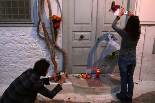 Des gens prennent en photos les messages et les fleurs déposées en mémoire de Leonard Cohen qui possédait une maison sur l'île grecque d'Hydra, le 11 novembre 2016


