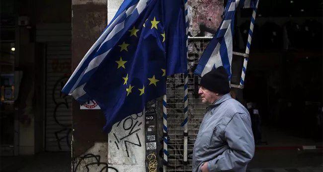Un passant dans une rue d'Athènes, samedi. Le Premier ministre grec, Alexis Tsipras, semble déterminé à résister aux exigences du ministre des Finances allemand et du FMI. - Photo Tzortzinis/AFP


