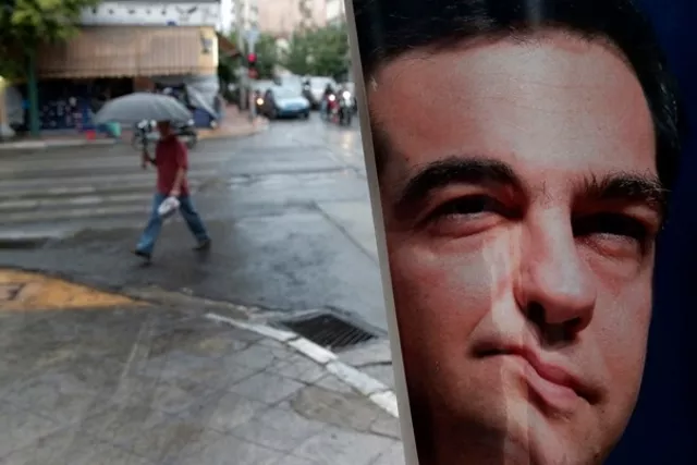 Un Grec passe aux côtés d'une affiche du premier ministre Alexis Tsipras, déformée par la pluie. Image: Keystone


