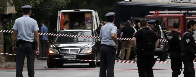 Des policiers sécurisent la zone autour de la voiture de l'ex-premier ministre Lucas Papademos, à Athènes. © Costas Baltas / Reuters


