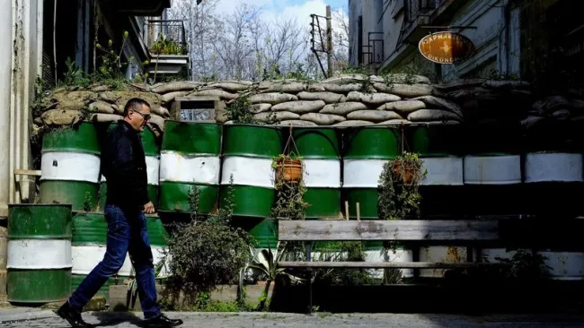 À Nicosie, un mur sépare la zone contrôlée par les chypriotes grecs et la zone contrôlée par les chypriotes turcs. Les habitants se sont accomodés des barricades semblables à celle-ci, faites de barils et de sac de sable, qui bloquent les routes allant du nord de la ville au sud. Crédits photo : Petros Karadjias/AP


