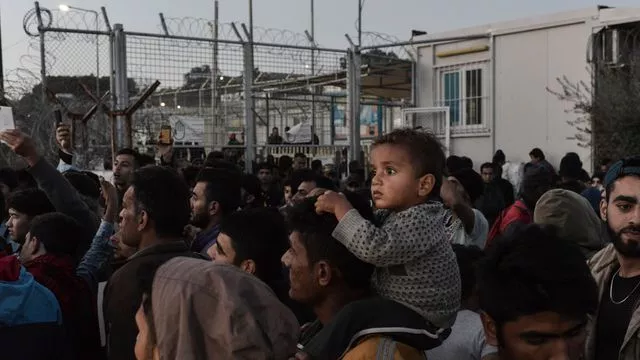 Un homme porte un enfant sur ses épaules lors d'une manifestation de réfugiés et migrants le 14 novembre 2017 à l'extérieur du camp de Moria à Mytilene, sur l'île grecque de Lesbos.



