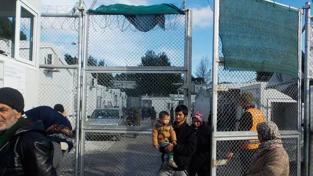 Des migrants avec un bébé sortent du camp migratoire de Moria, deuxième "ville" de l'île de Lesbos, le 21 décembre 2017 en Grèce


