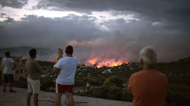 Des Grecs observent un feu de forêt à Rafina dans la banlieue d'Athènes, en Grèce, le 23 juillet 2018


