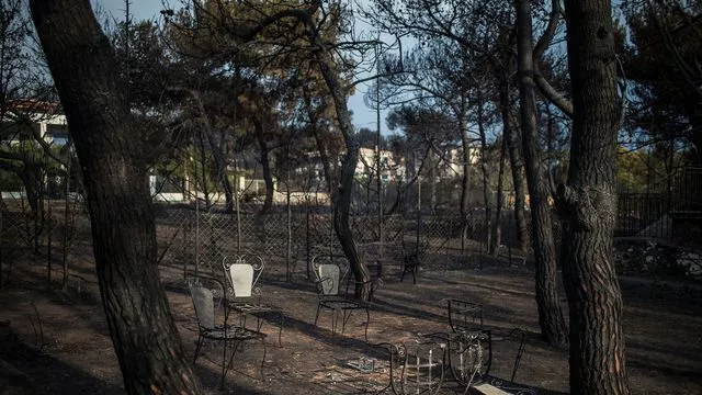 Une table et des chaises brûlées subsistent encore dans un jardin le 24 juillet 2018 après l'incendie meurtrier qui a dévasté Mati près d'Athènes



