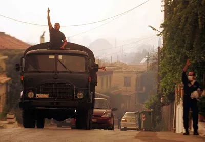 En guerre contre le feu. Des soldats évacuent un village en feu près de l'Olympie
